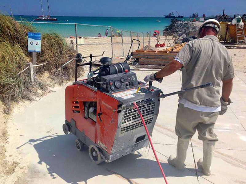 A man is using a concrete machine on a beach, creating an artwork for a gallery.